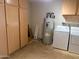 Spacious utility room with multiple storage cabinets, water heater, washer, and dryer at 9708 W Redwood Dr, Sun City, AZ 85351