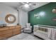 Stylish Bedroom boasts designer crib, green accent wall, and woven wall decor at 12211 W Hide Trl, Peoria, AZ 85383