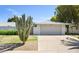 Home exterior featuring a two-car garage, a desert landscaped yard with a large cactus, and a decorative gate at 12826 W Maplewood Dr, Sun City West, AZ 85375