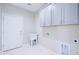 Laundry room with tile floors, white cabinets, and utility sink at 12940 W Tara Ln, Surprise, AZ 85374