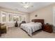 Serene main bedroom boasts a neutral color palette, fan, large bay windows, and plush carpeting at 15452 W Skyview Way, Surprise, AZ 85374
