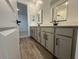 Bathroom featuring a double vanity with gray cabinets, modern black fixtures, and stylish wood-look tile flooring at 15794 W Cheryl Dr, Waddell, AZ 85355