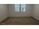 Cozy bedroom with plush carpeting, neutral walls, and a bright window providing natural light at 15794 W Cheryl Dr, Waddell, AZ 85355