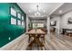 Open dining room with green accent wall, wood table, and modern chandelier flowing into living areas at 17980 W Meadowbrook Ave, Goodyear, AZ 85395