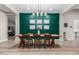 Modern dining room with stylish chandelier, green accent wall, and wood table with chairs at 17980 W Meadowbrook Ave, Goodyear, AZ 85395