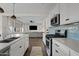 Modern kitchen boasts white cabinets, stainless steel appliances, and stylish blue tile backsplash, open to the living room at 1800 S Jesse Pl, Chandler, AZ 85286