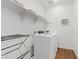 Clean laundry room featuring a new white washer and dryer, with shelves for extra storage space at 1800 S Jesse Pl, Chandler, AZ 85286