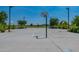 A basketball court with multiple hoops, shaded by trees, and well-maintained pavement at 22851 S 229Th Pl, Queen Creek, AZ 85142