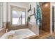 Bright bathroom showcasing a tub with a stylish brown-tiled shower and a window at 3611 E Dartmouth Cir, Mesa, AZ 85205