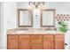Bathroom with dual sinks, framed mirrors, and wood-finished cabinetry at 3828 N Rosewood Ave, Avondale, AZ 85392