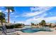 Resort-style community pool and lake, featuring lounge chairs, palm trees, and clear blue skies at 3828 N Rosewood Ave, Avondale, AZ 85392