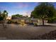 Stunning single-story home with desert landscaping, large mature tree and a spacious three-car garage at dusk at 4212 W Tierra Buena Ln, Phoenix, AZ 85053