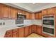 Well-lit kitchen with wood cabinetry, stainless steel appliances, white countertops and a glass tile backsplash at 4212 W Tierra Buena Ln, Phoenix, AZ 85053