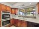 Modern kitchen with built-in stainless steel oven, cherry cabinets, and double basin sink overlooking backyard at 4212 W Tierra Buena Ln, Phoenix, AZ 85053