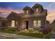 Charming home with stone accents, a covered porch, manicured landscaping, and a well-kept lawn at twilight at 4302 E Cynthia St, Gilbert, AZ 85295