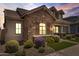 Home with stone accents, manicured landscaping, including colorful flowering bushes, and a well-kept lawn at sunset at 4302 E Cynthia St, Gilbert, AZ 85295