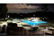 Night view of an outdoor pool with lounge chairs, umbrellas, and manicured landscaping and dark sky at 4303 E Cactus Rd # 128, Phoenix, AZ 85032