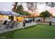 Entertaining backyard with putting green, shaded seating area, outdoor dining set, and lush landscaping at 5338 E Hearn Rd, Scottsdale, AZ 85254