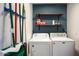 Functional laundry room with white washer and dryer, utility shelves, and wall-mounted organization for cleaning supplies at 5338 E Hearn Rd, Scottsdale, AZ 85254