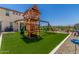 Large backyard with artificial turf, a playground, patio furniture, and a grill at 5516 N 193Rd Ave, Litchfield Park, AZ 85340