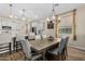 Dining area featuring a large wooden table, upholstered chairs, modern lighting, and access to the kitchen at 5516 N 193Rd Ave, Litchfield Park, AZ 85340