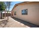 Backyard showcasing a stucco home exterior, brick pathway, pergola, and low-maintenance desert landscaping at 874 E Lamonte St, San Tan Valley, AZ 85140