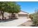 Lovely home featuring a well-kept lawn, mature trees, and a two-car garage, creating an inviting curb appeal at 874 E Lamonte St, San Tan Valley, AZ 85140