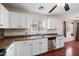 Bright kitchen featuring white cabinets, stainless steel dishwasher and sink, complemented by stylish flooring and a window at 874 E Lamonte St, San Tan Valley, AZ 85140