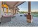 Inviting covered patio with stylish wicker furniture, brick pavers, and charming string lights, perfect for outdoor living at 9183 W Shamel Ash Rd, Peoria, AZ 85383