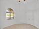Neutral bedroom with neutral paint, tile floor, and arched window bringing in natural light at 9183 W Shamel Ash Rd, Peoria, AZ 85383