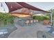Outdoor entertaining space featuring a covered bar area, seating, and lush landscaping at 9183 W Shamel Ash Rd, Peoria, AZ 85383