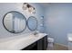 Stylish bathroom featuring dual circular mirrors, vanity with modern light fixtures and blue accent wall at 923 E Randy St, Avondale, AZ 85323