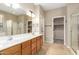 Bright bathroom featuring double sinks, wood cabinetry, a glass shower, and tile floors at 9465 W Tonopah Dr, Peoria, AZ 85382