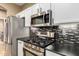 Kitchen featuring stainless steel appliances, mosaic tile backsplash, and white cabinets at 9465 W Tonopah Dr, Peoria, AZ 85382