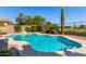 Lush landscaping surrounding a kidney-shaped pool with stone trim and a built-in step, perfect for leisure at 9465 W Tonopah Dr, Peoria, AZ 85382