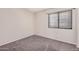 Carpeted bedroom featuring a large window with blinds and light, neutral-colored walls at 105 W Monona Dr, Phoenix, AZ 85027