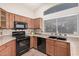 Kitchen with wood cabinets, black appliances, a large window, and sleek black double basin sink at 105 W Monona Dr, Phoenix, AZ 85027