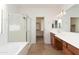Bright bathroom features a shower, a soaking tub, tile floors, and wooden cabinets at 14436 W Ventura St, Surprise, AZ 85379