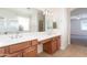 Bright bathroom with dual sinks, white counter tops, wood cabinets, tile floor, and shower at 14436 W Ventura St, Surprise, AZ 85379