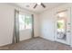 Carpeted bedroom with a window, ceiling fan, and a door leading to outdoor living area at 14436 W Ventura St, Surprise, AZ 85379