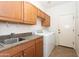 Well-equipped laundry room with sink, counter space, and wooden cabinets over the washer and dryer at 14436 W Ventura St, Surprise, AZ 85379