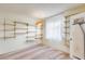 Bedroom with shelving and carpeted floors featuring an ironing board and a window with sheer curtains at 15608 N 57Th Dr, Glendale, AZ 85306