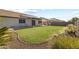 A spacious backyard featuring green grass, desert landscaping, a playset, and patio area at 15969 W Adams St, Goodyear, AZ 85338