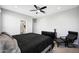A clean bedroom with a dark comforter, ceiling fan, and two sunny windows at 16528 W Pedro Ln, Goodyear, AZ 85338