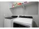 Well-equipped laundry room with modern, white appliances and upper shelf storage for supplies at 16528 W Pedro Ln, Goodyear, AZ 85338