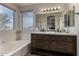 Bathroom featuring a soaking tub, dual sinks, and a large mirror providing a spa-like experience at 18854 N 73Rd Dr, Glendale, AZ 85308
