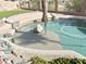 A beautifully designed pool area with a built-in umbrella, rock accents, and artificial turf, perfect for outdoor relaxation at 2053 E Clubhouse Dr, Phoenix, AZ 85048