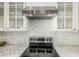 Modern kitchen featuring stainless steel range hood over a black cooktop and mosaic tile backsplash at 2542 E Los Alamos St, Gilbert, AZ 85295