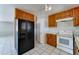 A kitchen showcasing wood cabinetry, white countertops, black refrigerator, and a white range oven at 42 S Vineyard --, Mesa, AZ 85210