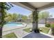 Inviting backyard with a uniquely shaped pool, greenery, and covered patio at 9805 W Caron Dr, Peoria, AZ 85345